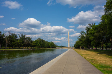 Washington Monument in Washington DC with across from the reflecting pond. Pictures taken  on a sunny summer day with a nice amount of clouds evenly spread out in the sky.