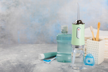 Electronic oral irrigator, toothbrush, paste, dental floss and mouthwash on a blue background....