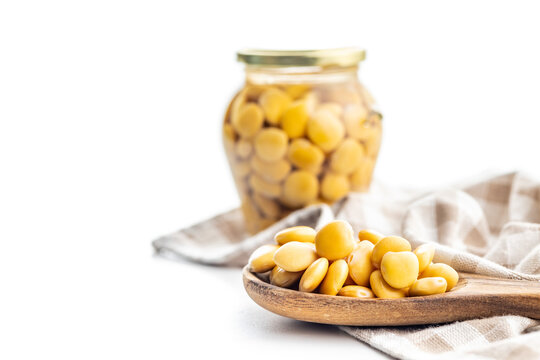 Lupini beans in brine. Pickled lupin in wooden spoon isolated on white background.