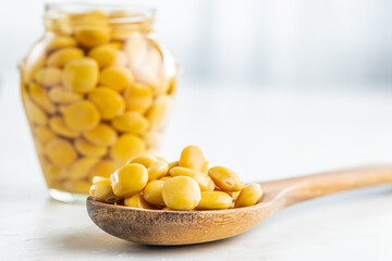 Lupini beans in brine. Pickled lupin on wooden spoon on kitchen table.