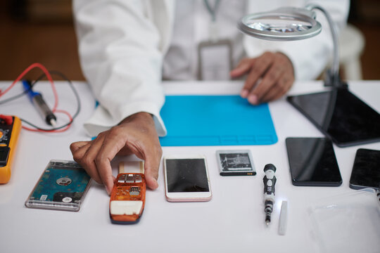 Closeup image of technician reparing feature phone,smartphone and hard drive, selective focus