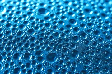 Drops of perspiration or rain on glass on a blue background. Bright background or backdrop. Macro. Selective focus