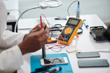 Engineer using multimeter when examining if smartphone works good after repairing