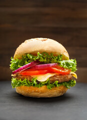 Juicy appetizing burger with beef on a dark background, homemade hamburger, fast food.