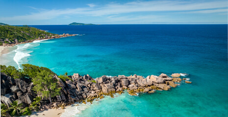 Aerial view of famous Grand Anse beach with big granite rocks on the La Digue island, Seychelles. Tropical landscape with sunny sky.