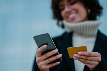 Young girl's hands holding a credit card and a smart phone while shopping online