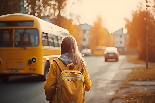 Girl with schoolbag waiting for yellow bus for school trip in autumn at urban street. Generative AI