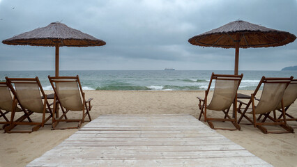 Calm sea waves rolling on empty sea beach at cold cloudy day. End of seasonal tourism, travel in winter.