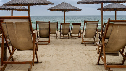 Row of empty wooden sunbeds on desert sea resort. End of seasonal tourism, travel in winter.
