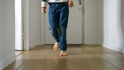 Little boy as running on a wooden floor in a long corridor at home. Happy childhood and the...