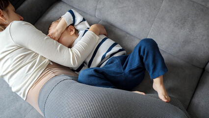 Mother breastfeeds her baby son on the sofa, surrounded by warmth and comfort. Concept of maternal care, child development, and the importance of breastfeeding.