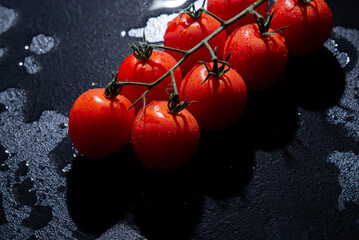 fresh tomatoes on black background with water drops
