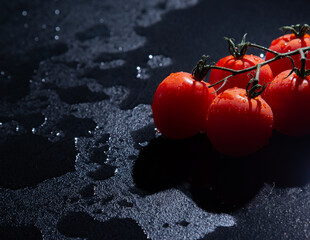 fresh tomatoes on black background with water drops