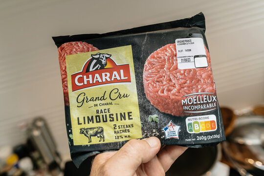 Paris, France - Jun, 3 2023: Hand holding Charal minced steak from limousine cow, showcasing Nutri-score index, reaching to pick finger food delicacy with care.