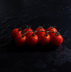 fresh tomatoes on black background with water drops