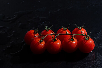 fresh tomatoes on black background with water drops
