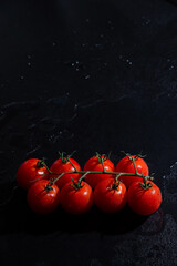 fresh tomatoes on black background with water drops