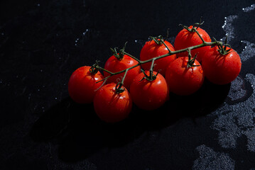 fresh tomatoes on black background with water drops