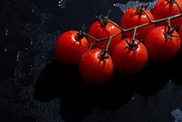 fresh tomatoes on black background with water drops