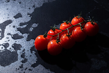 fresh tomatoes on black background with water drops