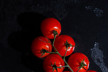fresh tomatoes on black background with water drops