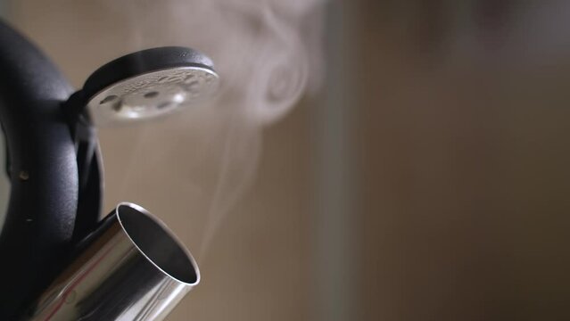 Hot steam comes out of the kettle on the stove. Slow motion