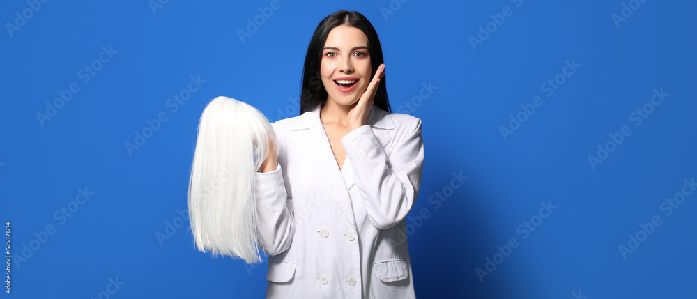 Wall mural excited young woman with wig on blue background