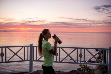 Portrait of an athlete who drinks water from a sports bottle. Maintaining water balance