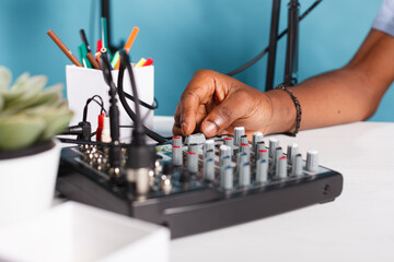 Man hand turning knob on sound controller equipment in studio close up. African american blogger...