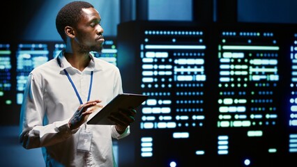 Serviceman in server hub walking through supercomputers used for computationally intensive tasks such as scientific simulations or 3D rendering. Worker doing annual equipment checkup