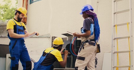 Experienced diverse teamworking workers cleaning air conditioner internal coolants, checking...