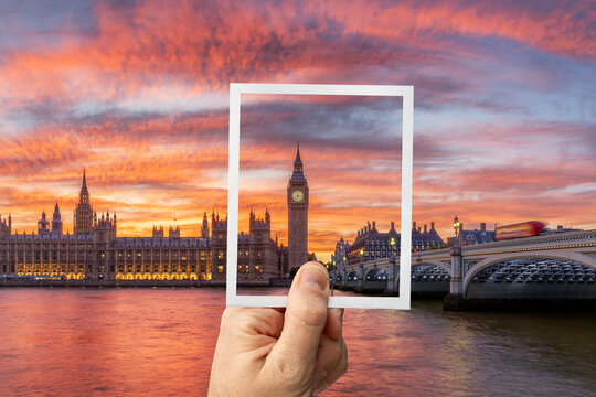 Hand holding up an instant photo picture of the Big Ben in London Great Britain with the actual landscape in the background