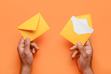 Male hands with envelopes and blank card on color background, closeup