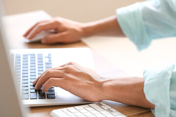 Male programmer working with laptop at table in office, closeup