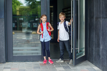 School children go to school, opening door. Back to school concept. Children with school backpacks.