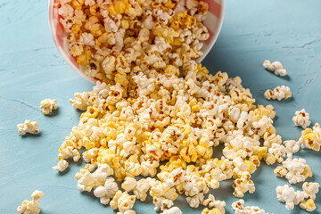 Bucket with tasty popcorn on blue background