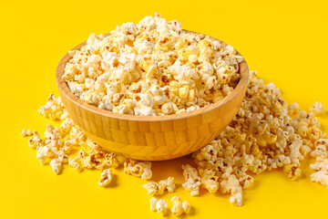Bowl with tasty popcorn on yellow background