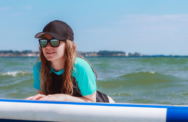 A beautiful young woman having fun on a sup in the sea. 