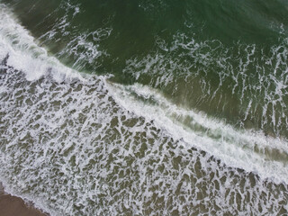 a stunning aerial view of the sea, with waves breaking against a sandy beach. 