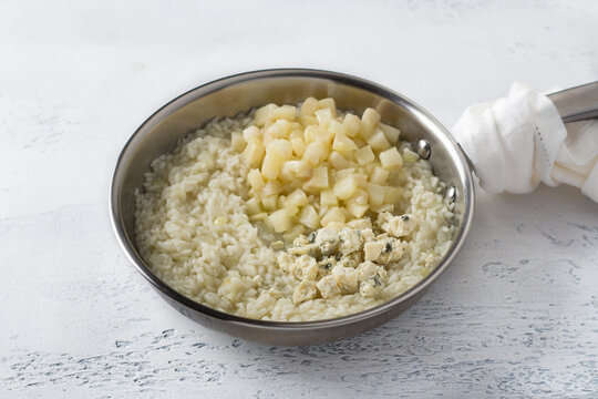 Frying pan risotto, cooking step by step, step 6, adding pear and blue cheese on a light blue background