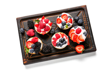 Board of tasty tartlets with whipped cream and berries on white background