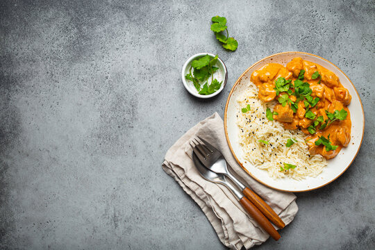 Traditional Indian Dish Chicken Curry With Basmati Rice And Fresh Cilantro On Rustic White Plate On Gray Concrete Table Background From Above. Indian Dinner Meal