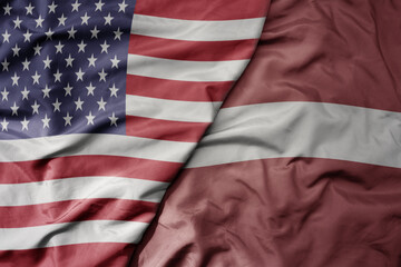 big waving colorful flag of united states of america and national flag of latvia .