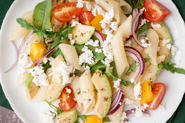 Plate of tasty pasta salad with tomatoes and avocado, closeup