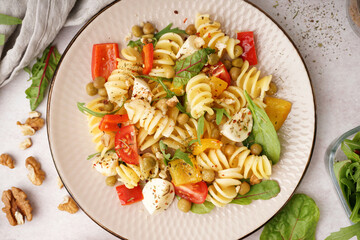 Plate of tasty pasta salad with pepper and peas on white background