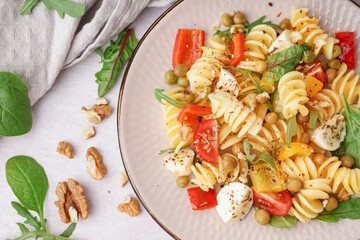 Plate of tasty pasta salad with pepper and peas on white background