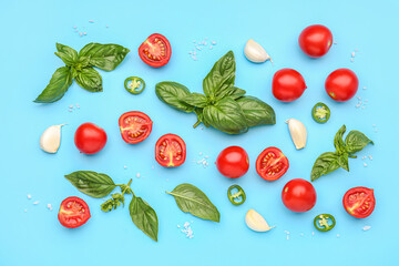Fresh basil, cherry tomatoes and garlic on blue background
