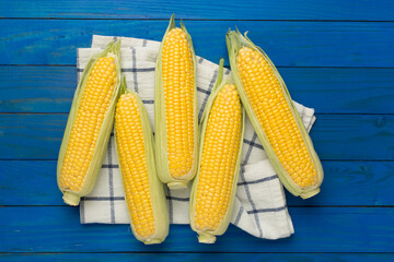 Fresh corn on cobs on wooden background, top view