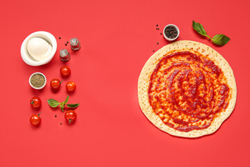 Pizza crust with tomato sauce and ingredients on red background