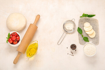 Raw dough and ingredients for preparing pizza on light background